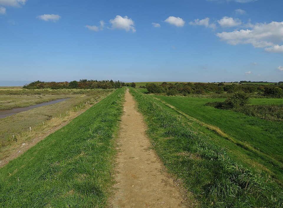 The Norfolk Coast Path running along a raised sea bank between salt marsh and reclaimed fields.